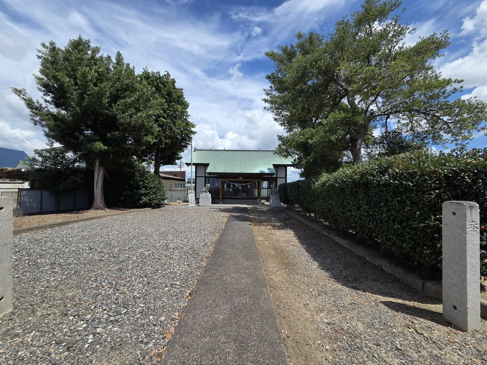 参道の入口から見た社殿。左右の木立と一対の狛犬に囲まれている。