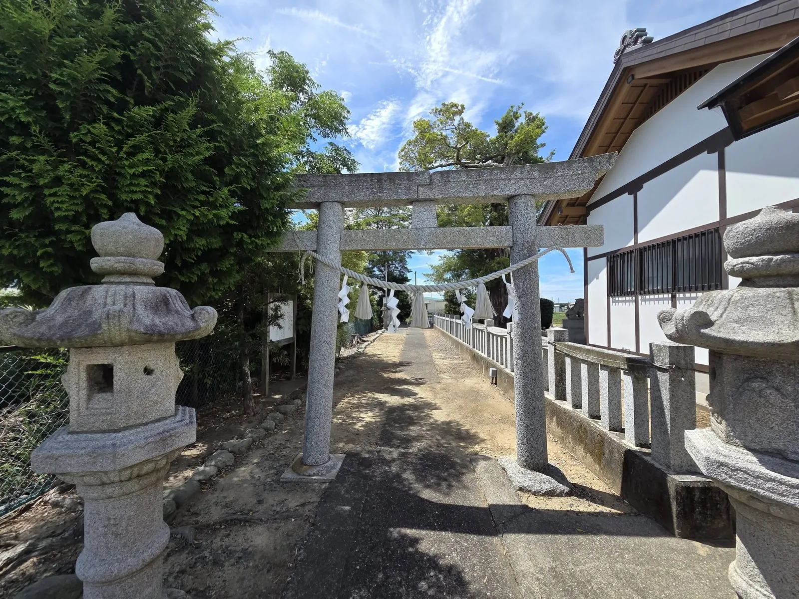 石造鳥居を正面から見た様子。奥に社殿の白壁が見える。