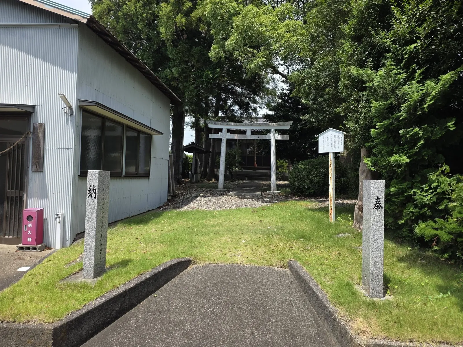 道路側から参道入口を望む。社号標と奉献標柱の奥に鳥居が見える。