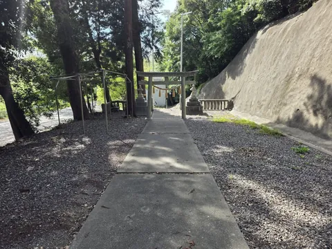 参道脇から見た鳥居と境内。左手に川沿いの道が見える。