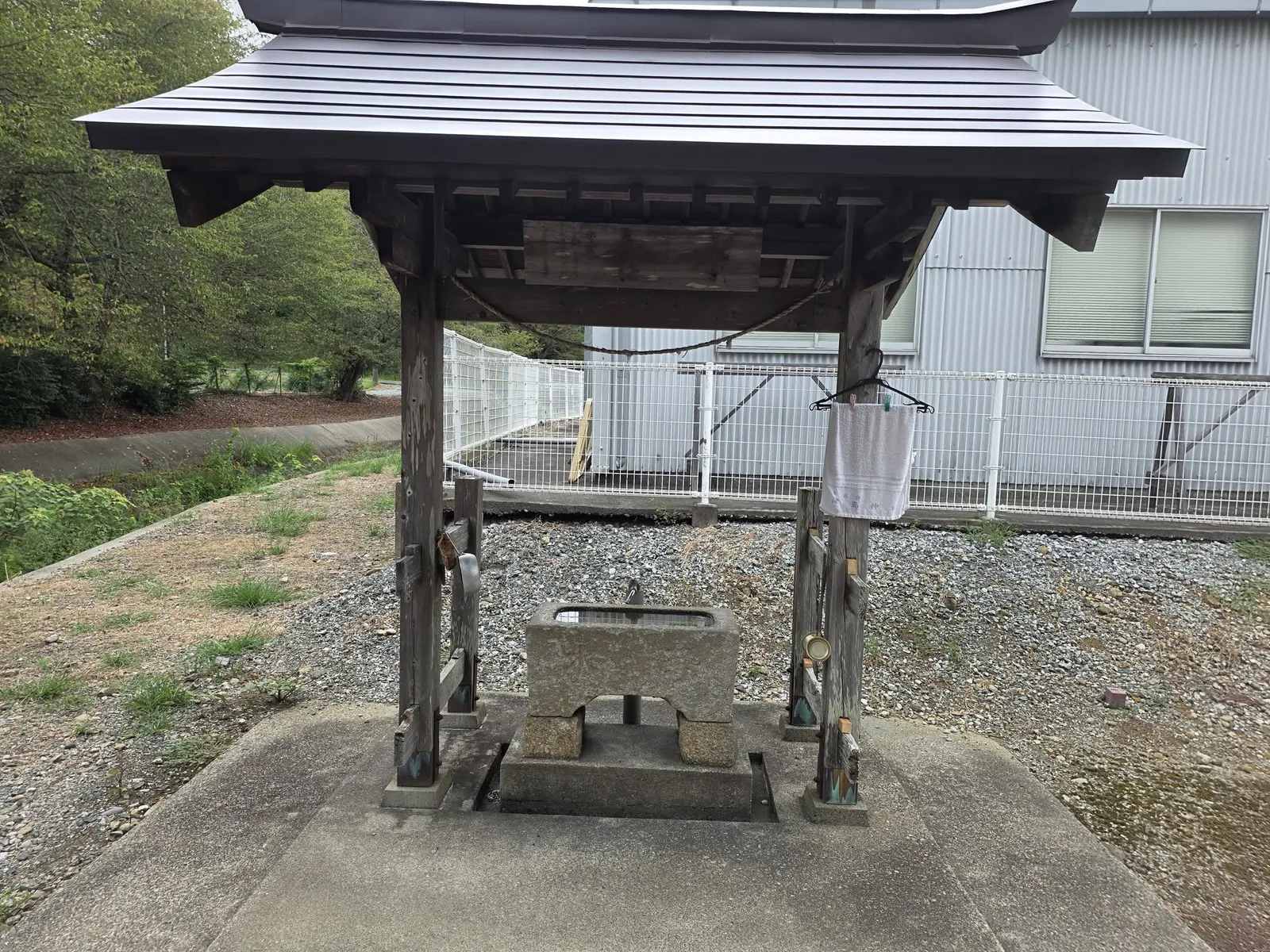 境内入口側の手水舎。木造屋根の下に石造手水鉢を据える。