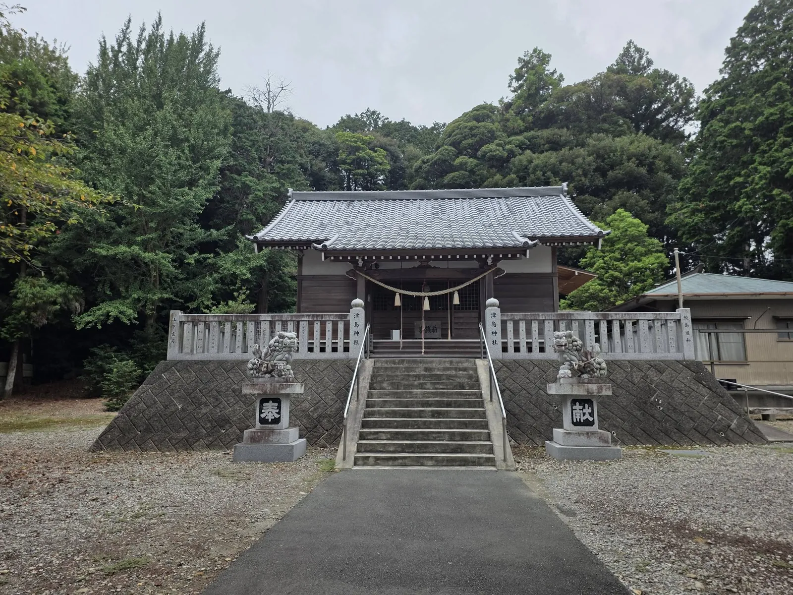 石段正面から見る社殿。石垣と玉垣を巡らせた高所に立つ。