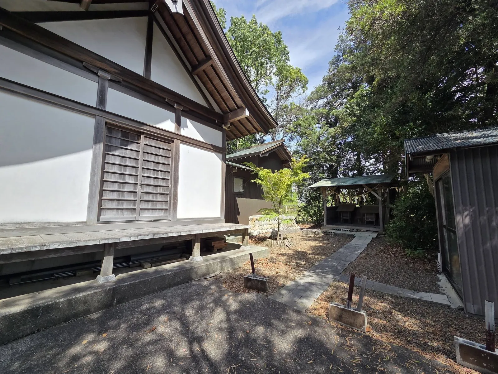 社殿の側面と境内の建物群。白壁の社殿と奥の境内社、附属の建物が木立の中に並ぶ。