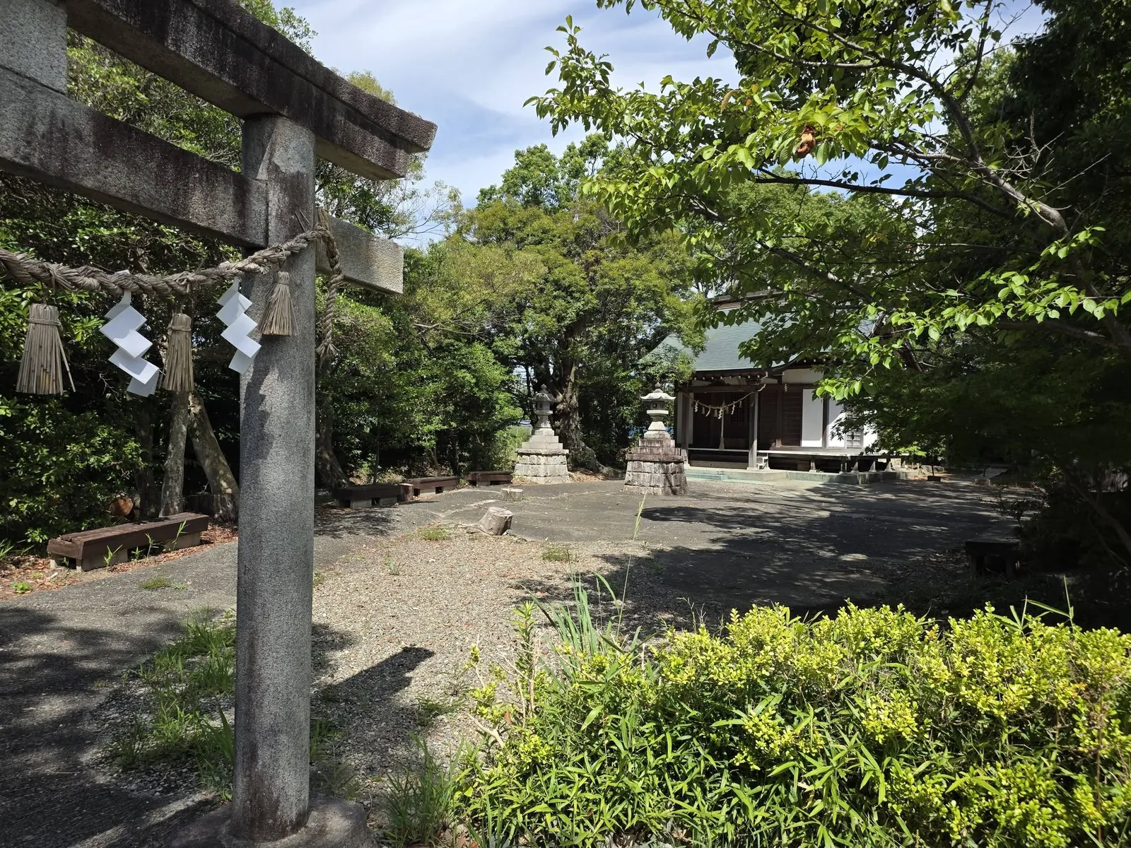 鳥居越しに見た境内。注連縄と紙垂の奥に石灯籠と社殿が見える。