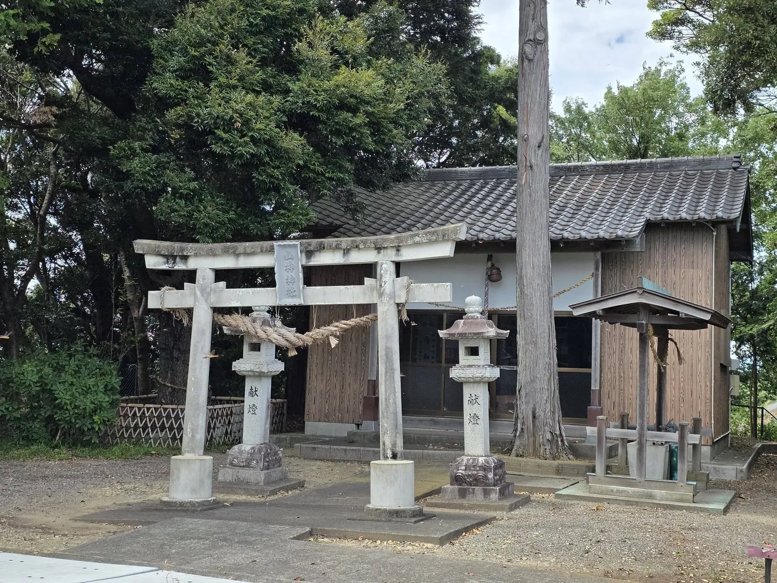 石造鳥居と社殿正面。鳥居の左右に石灯籠が立つ。