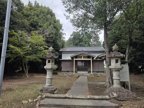 石灯籠越しに見る社殿。参道正面の奥に木造社殿が立つ。