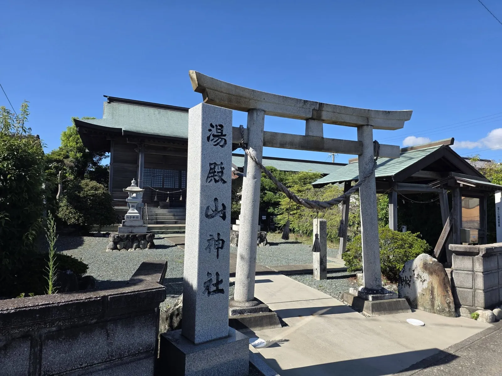 社号を刻む鳥居の柱と、奥に建つ湯殿山神社の社殿。