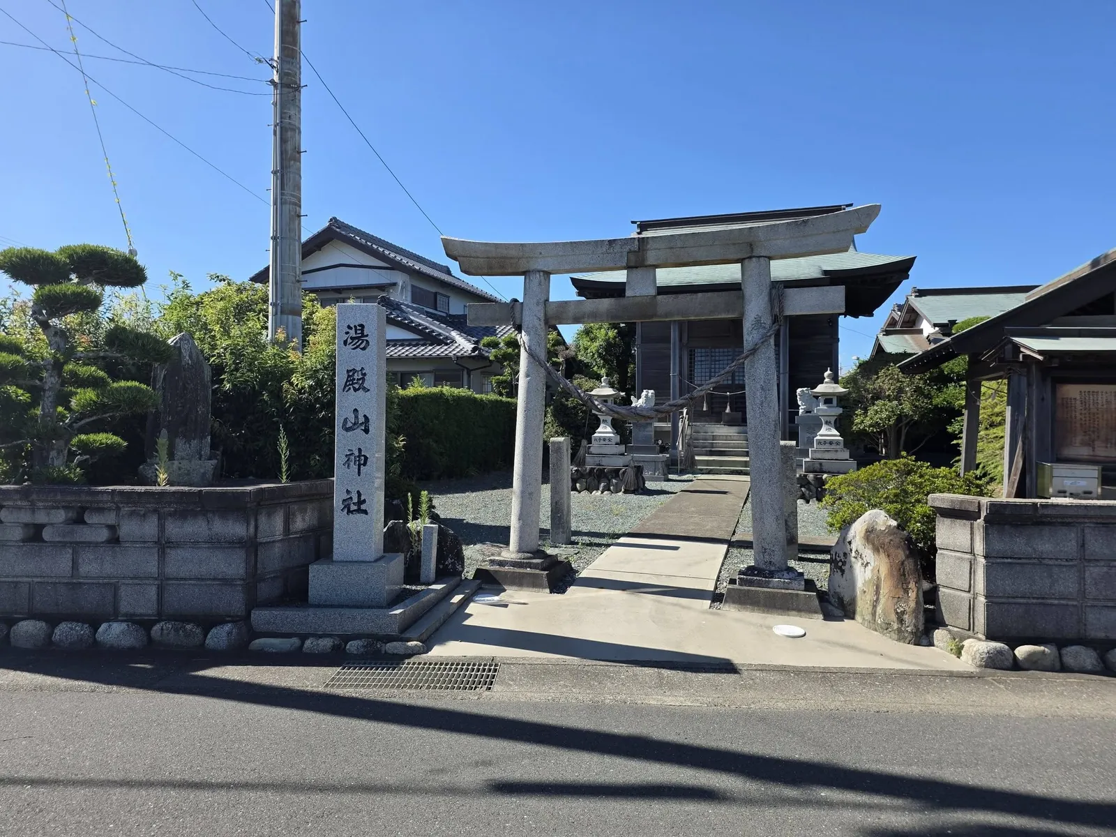 道路側から社号標・石造鳥居・社殿を望む。