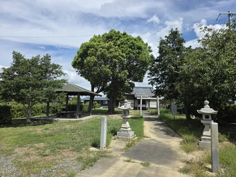 大木と四阿の奥に鳥居越しの社殿を望む境内全景。